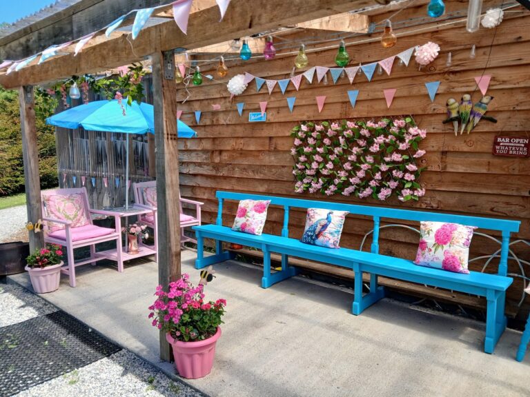 Covered terrace with blue benches, pink cushions and flower wall