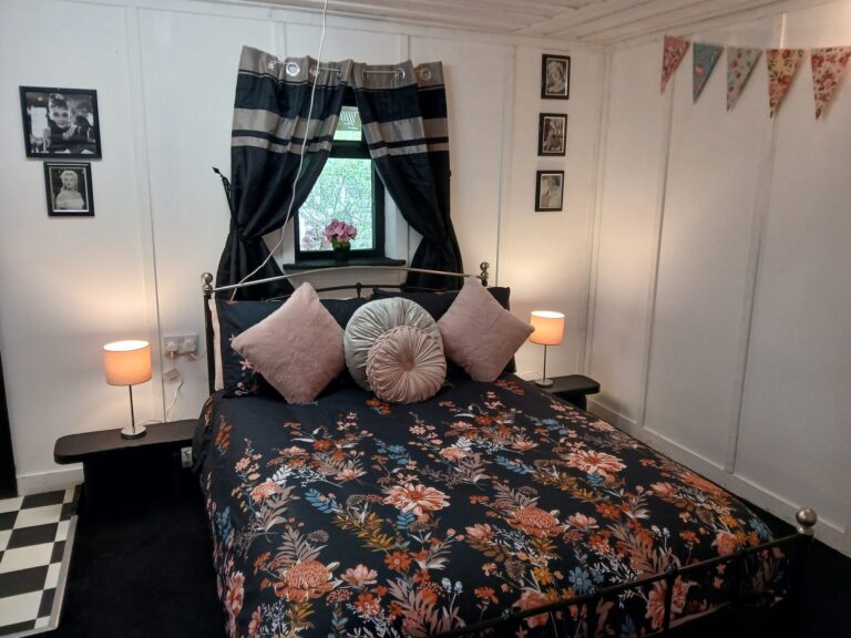 Double bedroom with floral bedspread and pink cushions