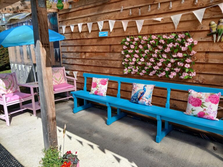 Long blue bench with pink cushions under bunting