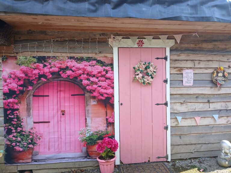 Pink cottage door surrounded by pink flowers
