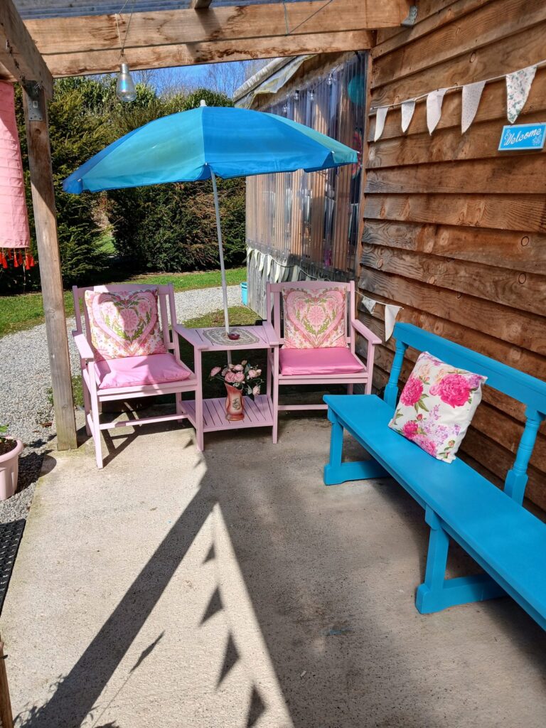Shaded seating area with pink chairs and blue parasol