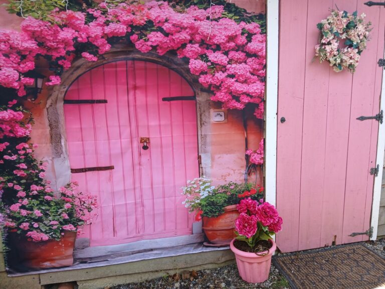 Pink arched cottage door framed with pink flowers