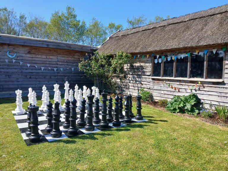 Giant garden chess set on the lawn beside the thatched cottages