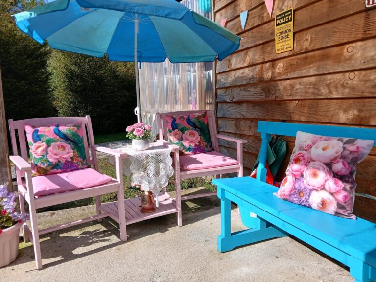 Pink garden chairs and table under a blue parasol